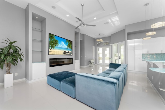 cinema featuring ceiling fan, built in features, light tile patterned floors, french doors, and a tray ceiling