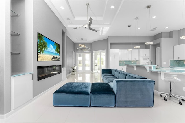 tiled living room featuring a raised ceiling, ceiling fan, and french doors