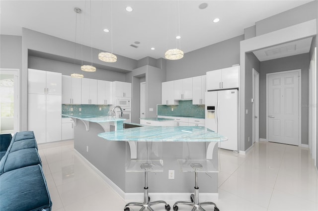 kitchen featuring pendant lighting, light tile patterned floors, white appliances, backsplash, and white cabinetry