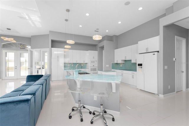 kitchen featuring pendant lighting, white cabinetry, white appliances, backsplash, and light tile patterned floors