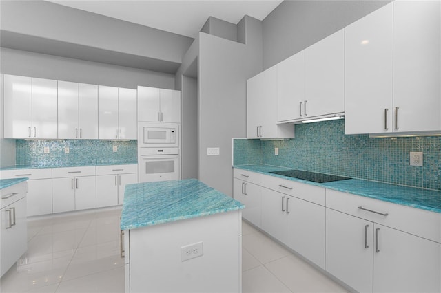 kitchen featuring light tile patterned floors, white appliances, backsplash, white cabinetry, and a center island