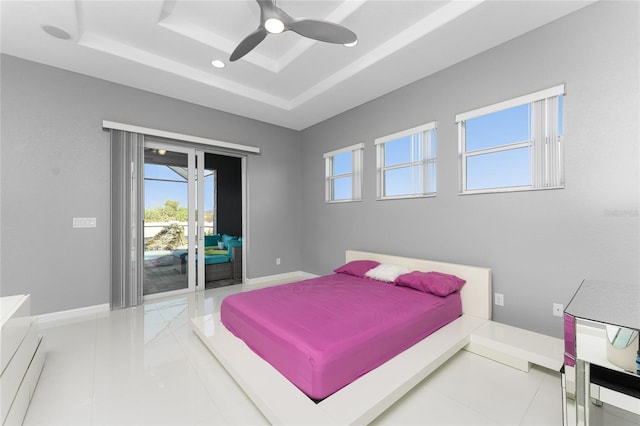 tiled bedroom featuring access to outside, a tray ceiling, and ceiling fan