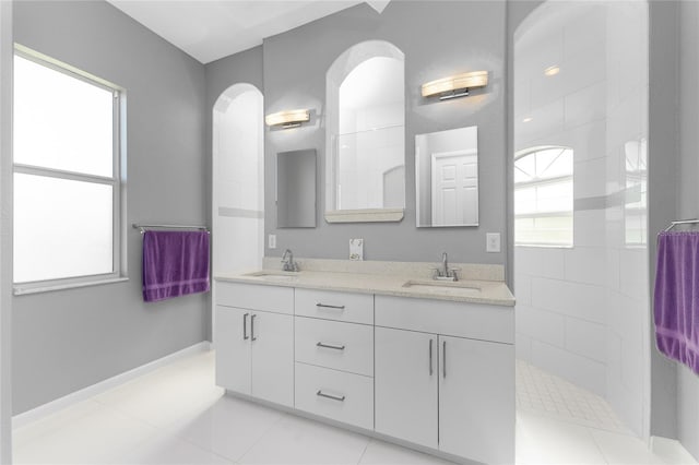 bathroom with a tile shower, tile patterned flooring, and vanity