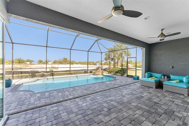 view of swimming pool featuring ceiling fan, glass enclosure, a patio, and pool water feature