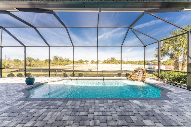 view of pool with pool water feature, glass enclosure, and a patio area