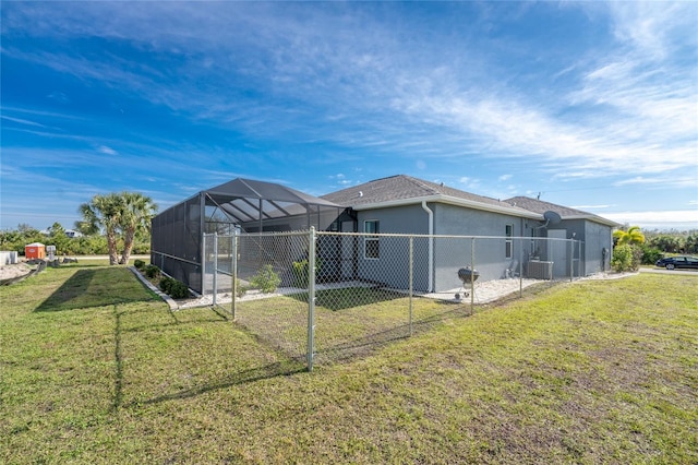 rear view of house featuring a lanai, central air condition unit, and a lawn