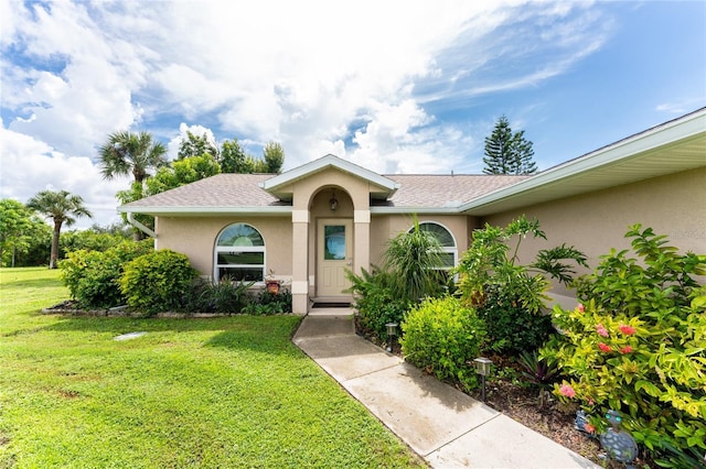 13511 Foresman Blvd, Port Charlotte, FL 33981 - view of front of home with roof with shingles, a front yard, and stucco siding