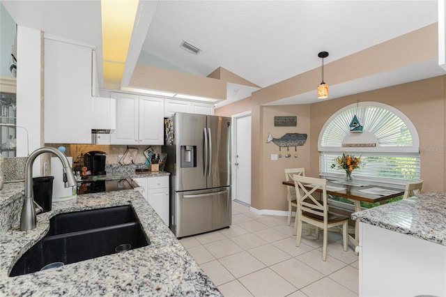 kitchen with pendant lighting, sink, white cabinets, lofted ceiling, and stainless steel fridge