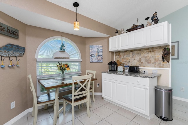 13511 Foresman Blvd, Port Charlotte, FL 33981 - kitchen with baseboards, backsplash, white cabinets, dark stone counters, and pendant lighting