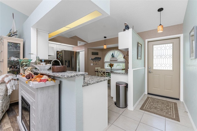 kitchen with pendant lighting, stainless steel fridge with ice dispenser, white cabinets, vaulted ceiling, and kitchen peninsula