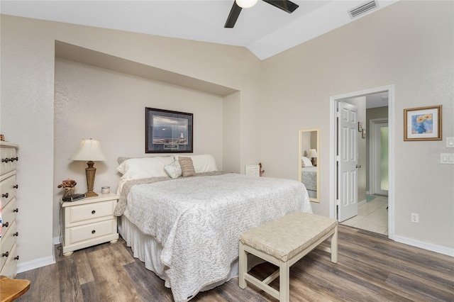 bedroom featuring ceiling fan, vaulted ceiling, connected bathroom, and dark hardwood / wood-style flooring