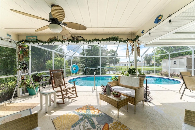 view of pool with glass enclosure, ceiling fan, and a patio