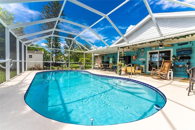 view of swimming pool with glass enclosure, ceiling fan, and a shed