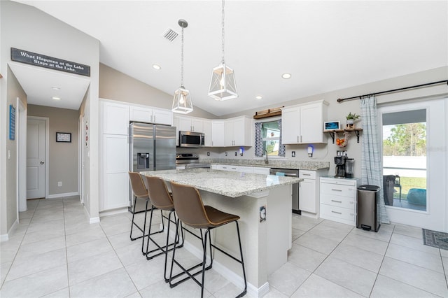 kitchen with appliances with stainless steel finishes, a healthy amount of sunlight, a center island, and vaulted ceiling