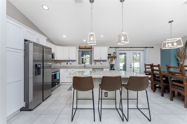 kitchen featuring a center island, stainless steel appliances, lofted ceiling, pendant lighting, and white cabinets