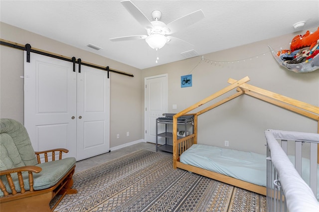 bedroom with a closet, ceiling fan, a textured ceiling, and a barn door