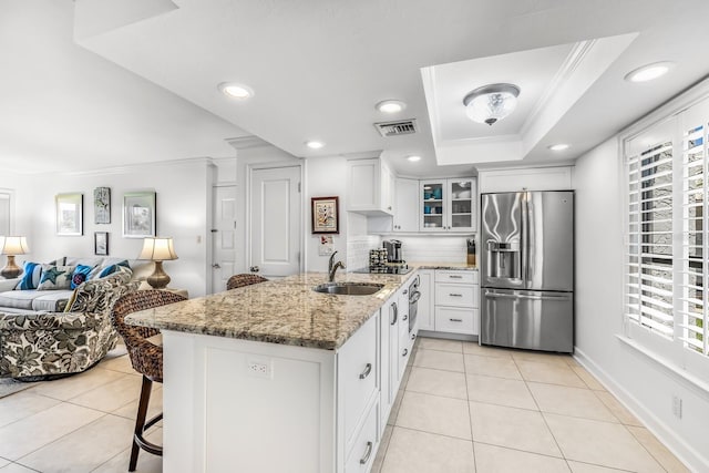 kitchen featuring kitchen peninsula, stainless steel fridge with ice dispenser, white cabinetry, light stone countertops, and sink