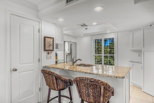 kitchen with white cabinetry, light stone counters, sink, and stainless steel refrigerator with ice dispenser