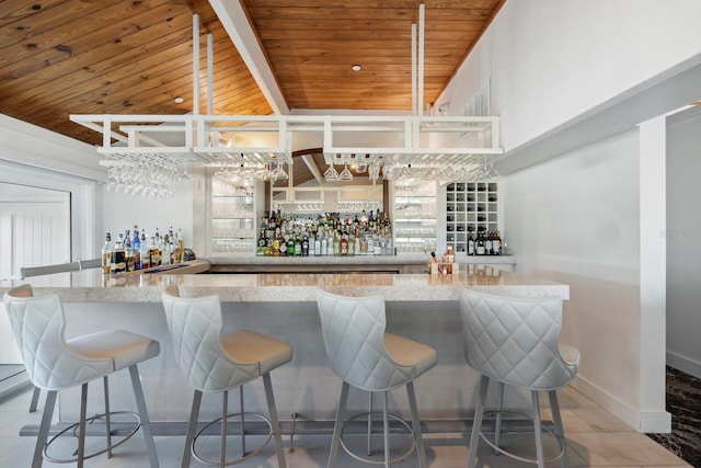 bar featuring vaulted ceiling, light tile patterned flooring, and wooden ceiling