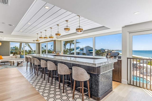 kitchen featuring a water view, light hardwood / wood-style floors, decorative light fixtures, and a center island