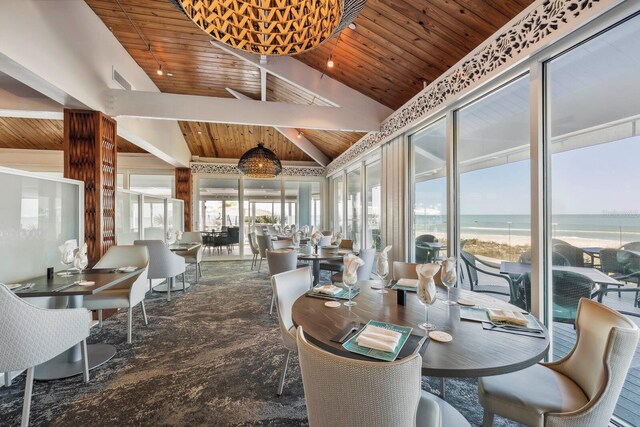 dining space featuring a water view, wood ceiling, lofted ceiling with beams, and a wealth of natural light