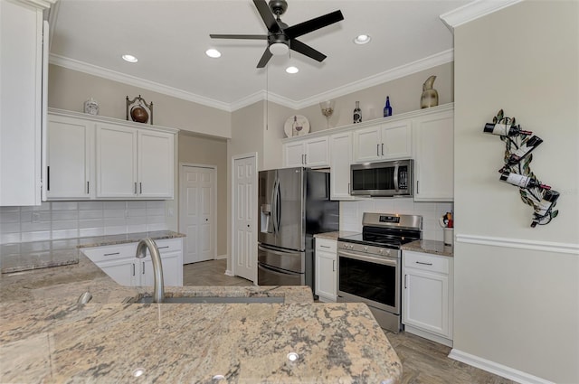 kitchen with white cabinetry, light stone countertops, stainless steel appliances, and sink