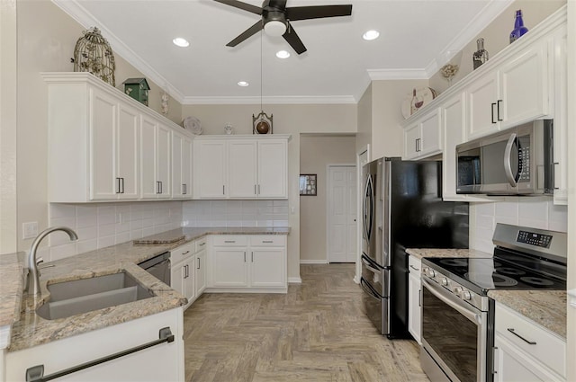 kitchen with light parquet flooring, sink, white cabinetry, stainless steel appliances, and light stone counters