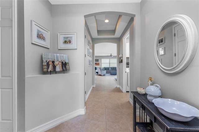 hallway featuring a raised ceiling and light tile patterned floors