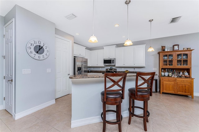 kitchen with pendant lighting, light tile patterned floors, white cabinetry, appliances with stainless steel finishes, and dark stone countertops