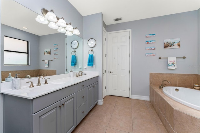 bathroom featuring tile patterned flooring, tiled bath, and vanity