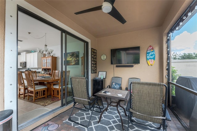 sunroom featuring ceiling fan with notable chandelier