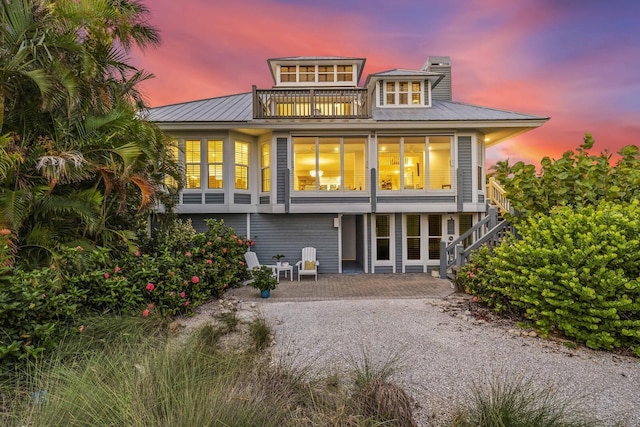 22 Seawatch Dr, Boca Grande, FL 33921 - back of property at dusk featuring a balcony, stairway, a patio, and a metal roof