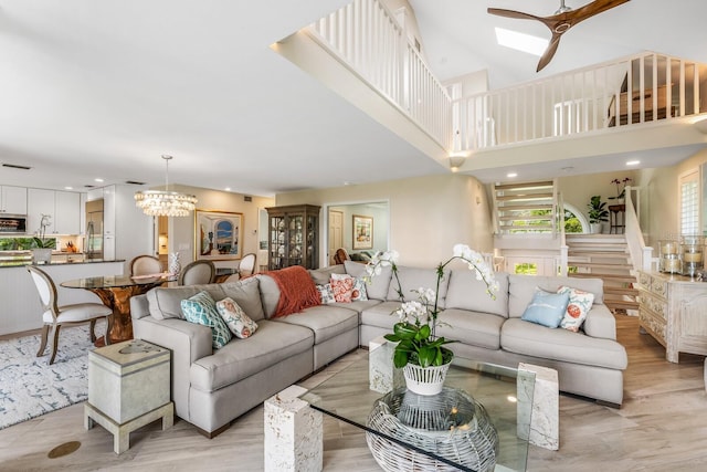 living room featuring ceiling fan with notable chandelier and light wood-type flooring