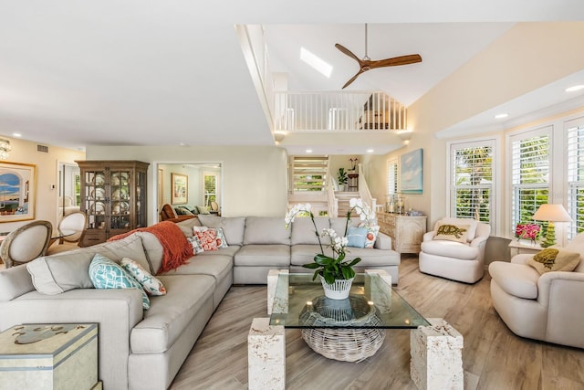 living room with light wood-type flooring, high vaulted ceiling, and ceiling fan