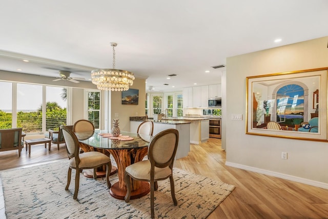 dining area featuring light hardwood / wood-style floors and ceiling fan with notable chandelier