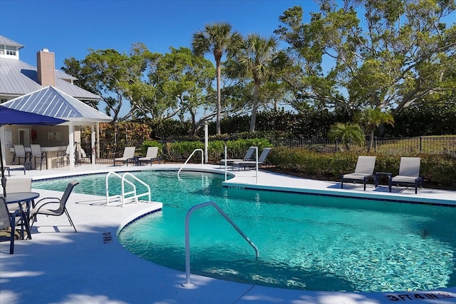 view of pool featuring exterior bar and a patio