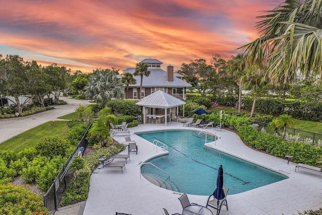 pool at dusk featuring a patio