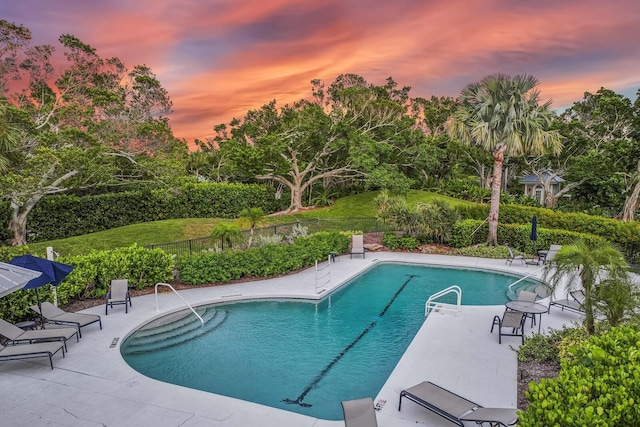 pool at dusk featuring a patio