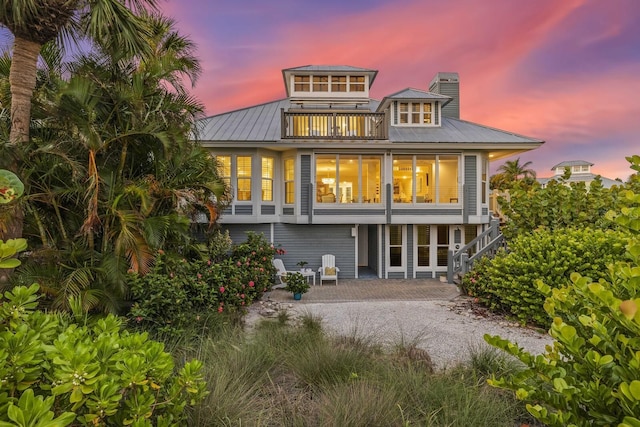 22 Seawatch Dr, Boca Grande, FL 33921 - back of house featuring a balcony, a patio, a chimney, and a metal roof