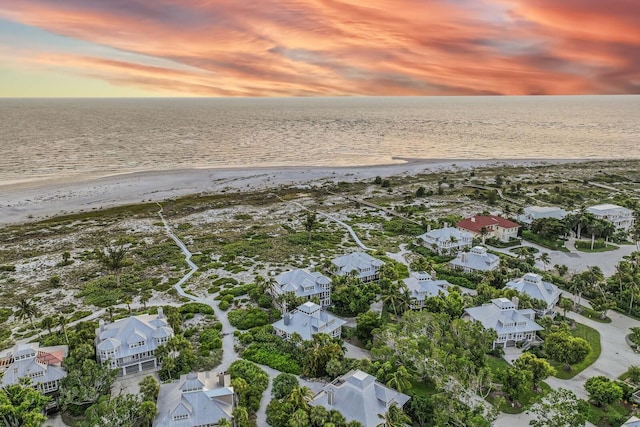 aerial view at dusk with a view of the beach and a water view