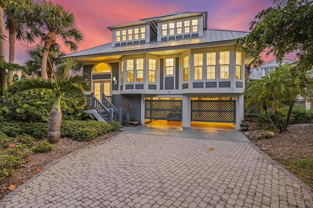 22 Seawatch Dr, Boca Grande, FL 33921 - raised beach house with decorative driveway, a standing seam roof, french doors, a metal roof, and stairway