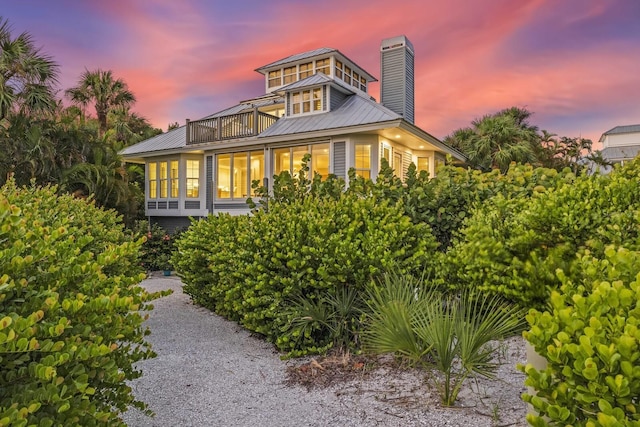 back house at dusk featuring a balcony