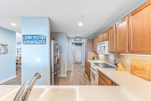 kitchen with tasteful backsplash, sink, white appliances, and light wood-type flooring