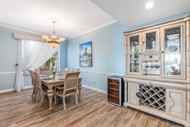 dining space featuring an inviting chandelier, beverage cooler, and crown molding