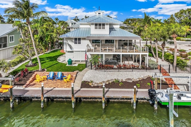 rear view of house with a water view, a yard, a balcony, and a patio