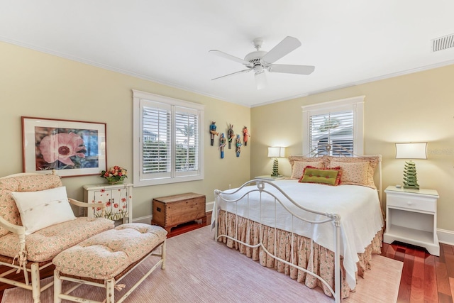 bedroom with ceiling fan, wood-type flooring, ornamental molding, and multiple windows