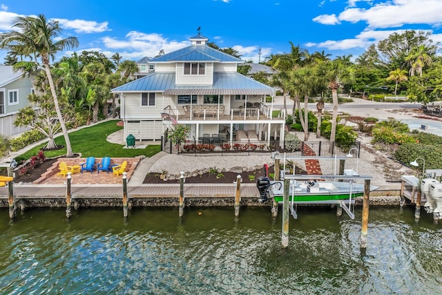 back of property featuring a yard, a balcony, and a water view