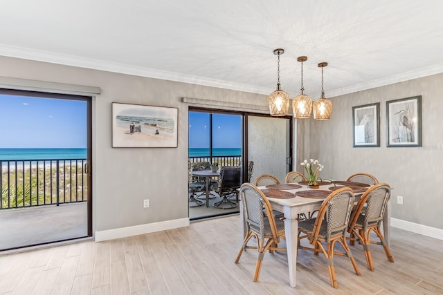 dining area featuring ornamental molding, a water view, and light hardwood / wood-style floors