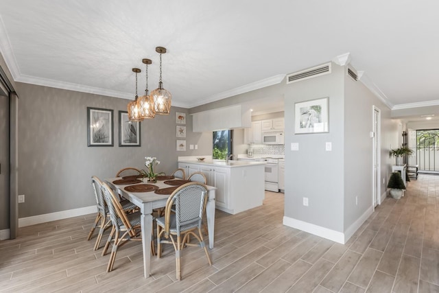 dining area featuring light hardwood / wood-style flooring, crown molding, and sink