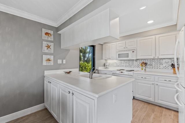 kitchen with sink, kitchen peninsula, white appliances, white cabinets, and ornamental molding